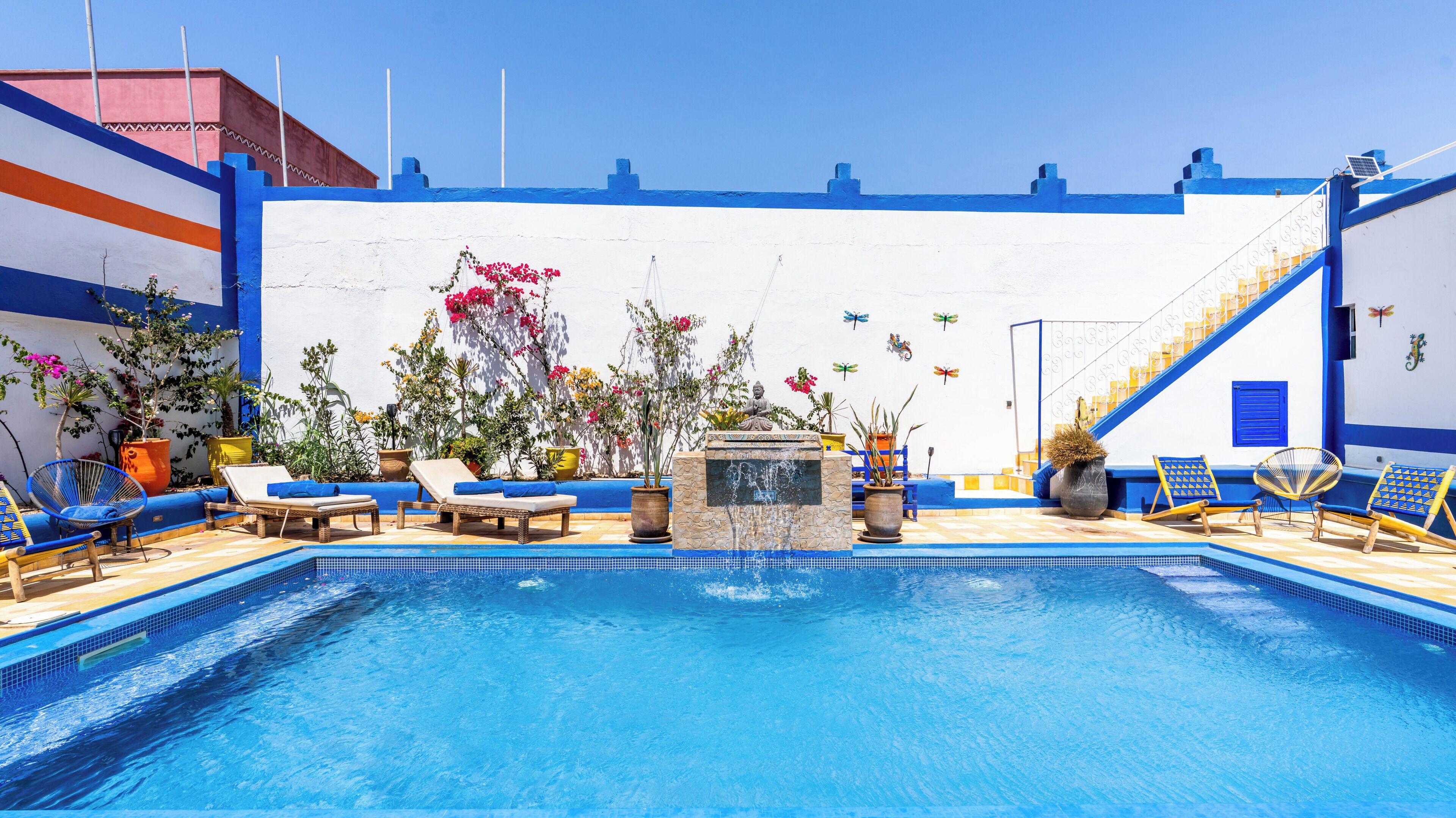 A swimming pool with lounge chairs and potted plants.