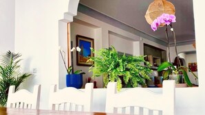 A room with a white wall, a wooden table, and a hanging light fixture. - Riad Ghazal (Essaouira)