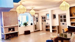 A modern living room with a fireplace, wooden shelves, and hanging lamps. - Riad Ghazal (Essaouira)
