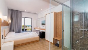 Habitación de hotel moderna con cama, escritorio, televisor, zona de ducha y vistas al exterior.
