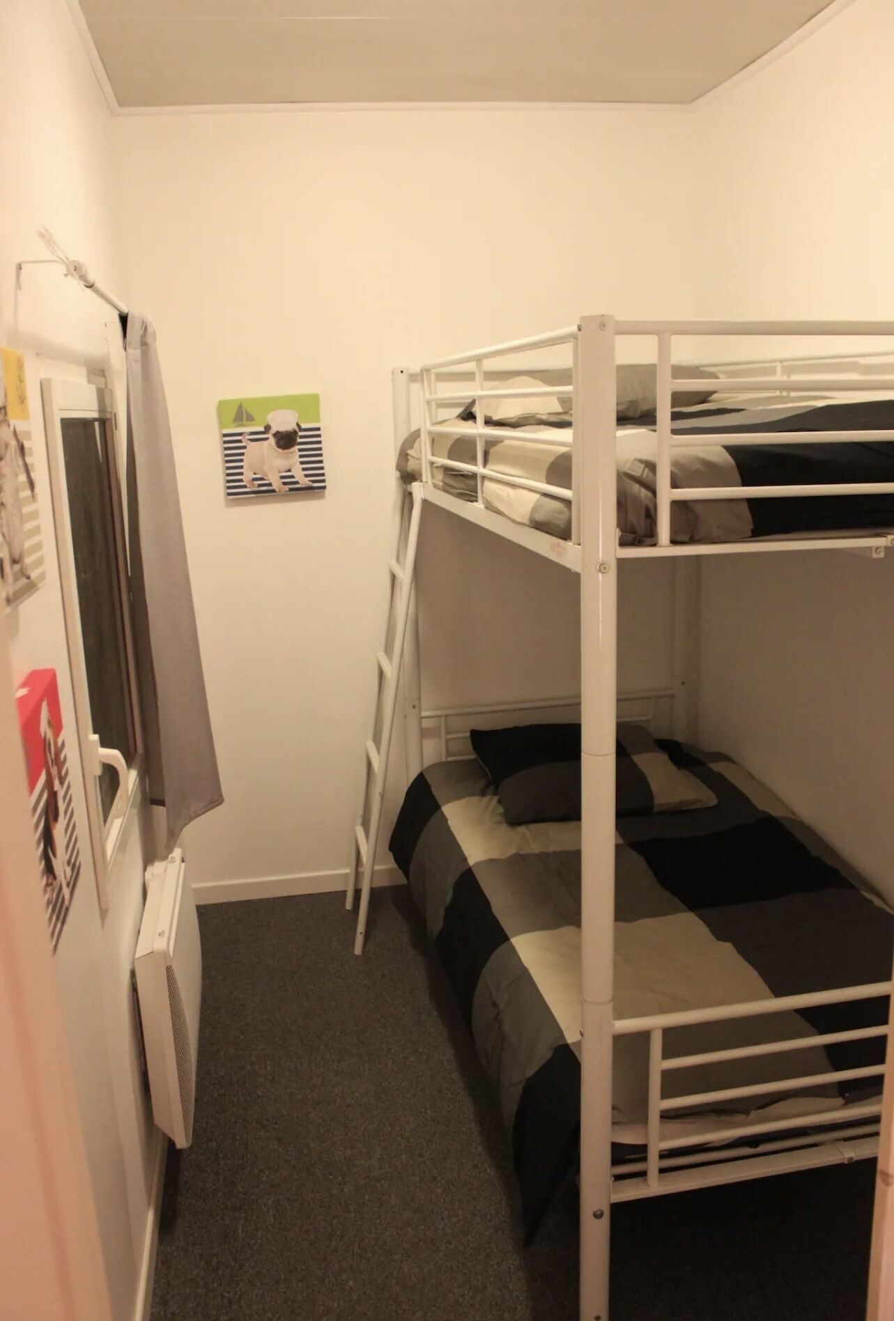 A bunk bed room with a ladder, a radiator, and a poster on the wall.