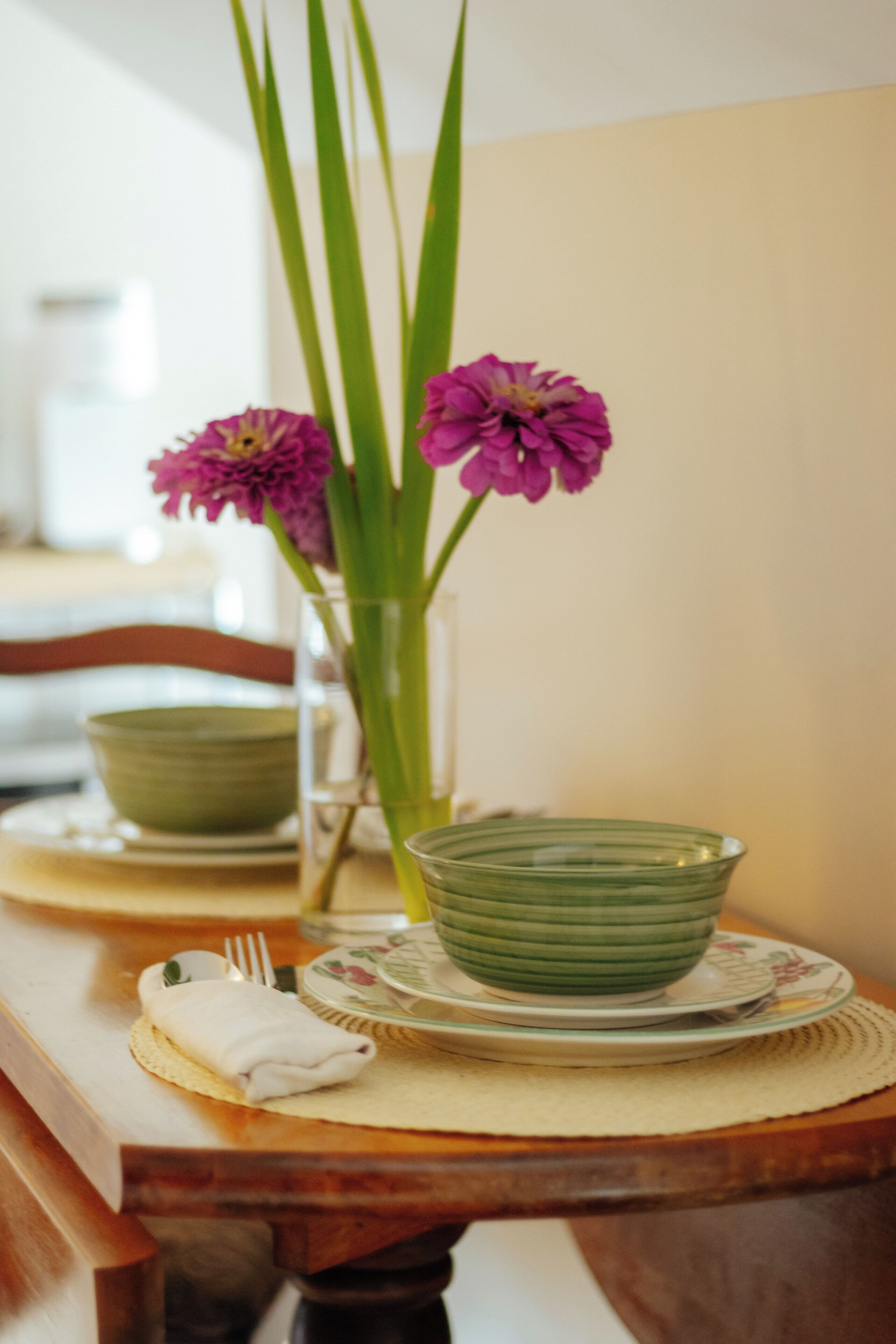 Una mesa de comedor con un tazón verde, un plato y una servilleta.