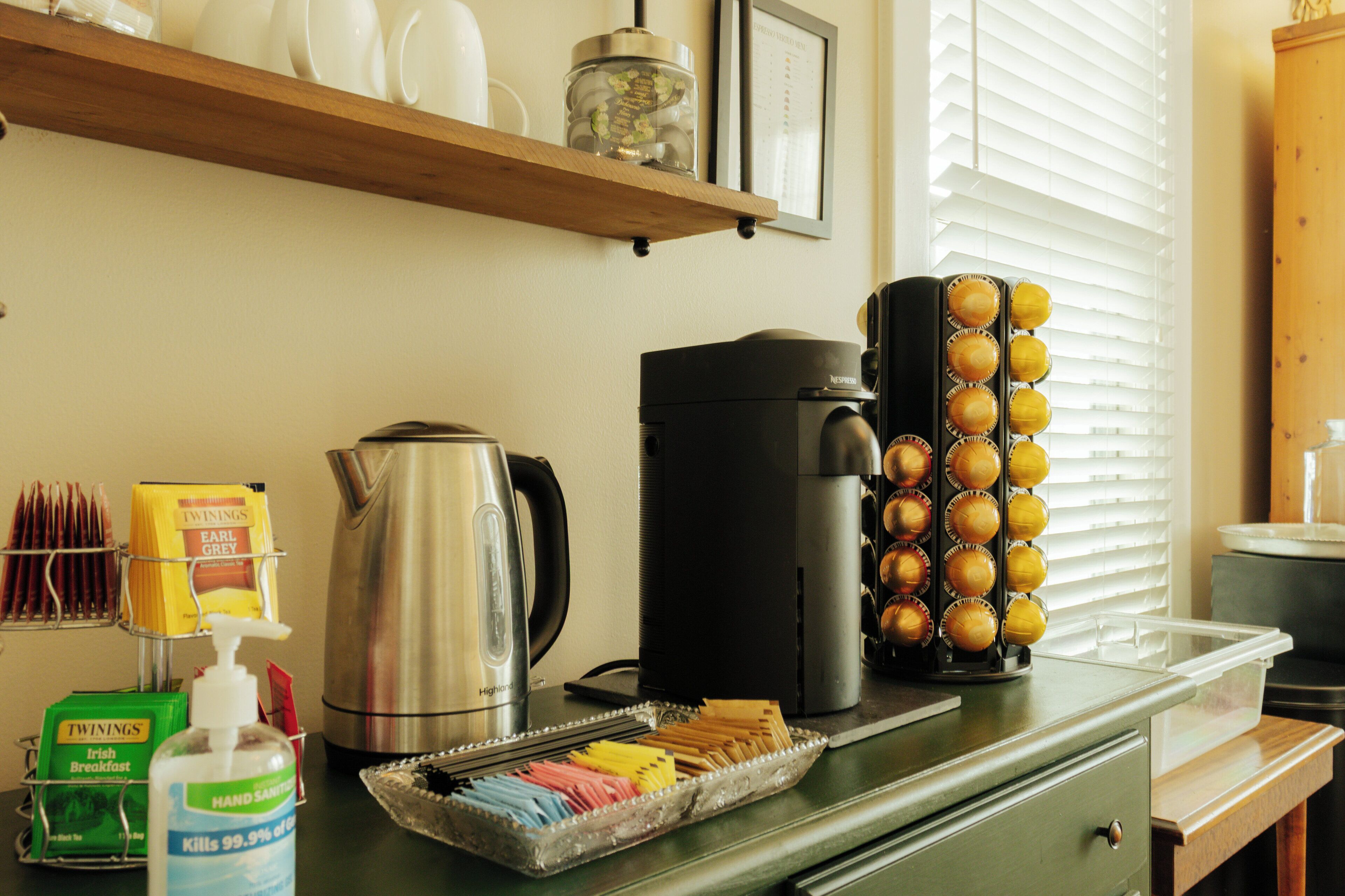 A kitchen counter with a coffee maker, a kettle, a muffin tray, and various breakfast items.