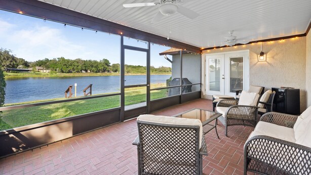 A covered patio with wicker furniture, a ceiling fan, and a view of a lake. - Centrally Located, Serene Luxury Retreat (Brandon)