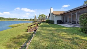 A modern house with a large glass window, a wooden deck, and a view of a lake. - Centrally Located, Serene Luxury Retreat (Brandon)