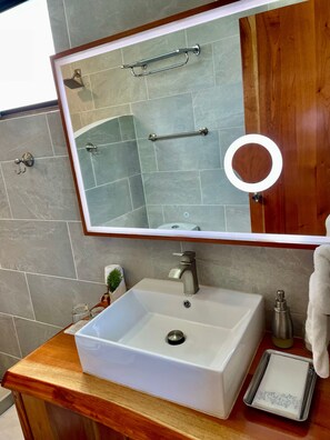 A bathroom with a white sink, a mirror, and a wooden vanity. - The Fruit Tree Garden Bromeliad Suite (Arenal)