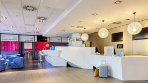 A modern hotel lobby with a reception desk, seating area, and a bar. - B&B Hotel Bremen-altstadt (Bremen)