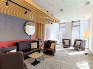 A modern lobby with a sofa, chairs, a small table, a mirror, and a lamp. - B&B Hotel Bremen-altstadt (Bremen)