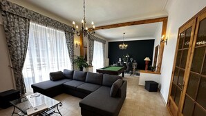 A modern living room with a sectional sofa, a pool table, and a billiards setup.