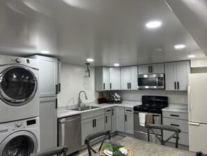 A modern kitchen with built-in appliances, grey cabinets, and a dining area with a table and chairs. - Cozy Mountain Retreat - Snowbasin, Skiing, Biking, Hiking, Fishing (Morgan)