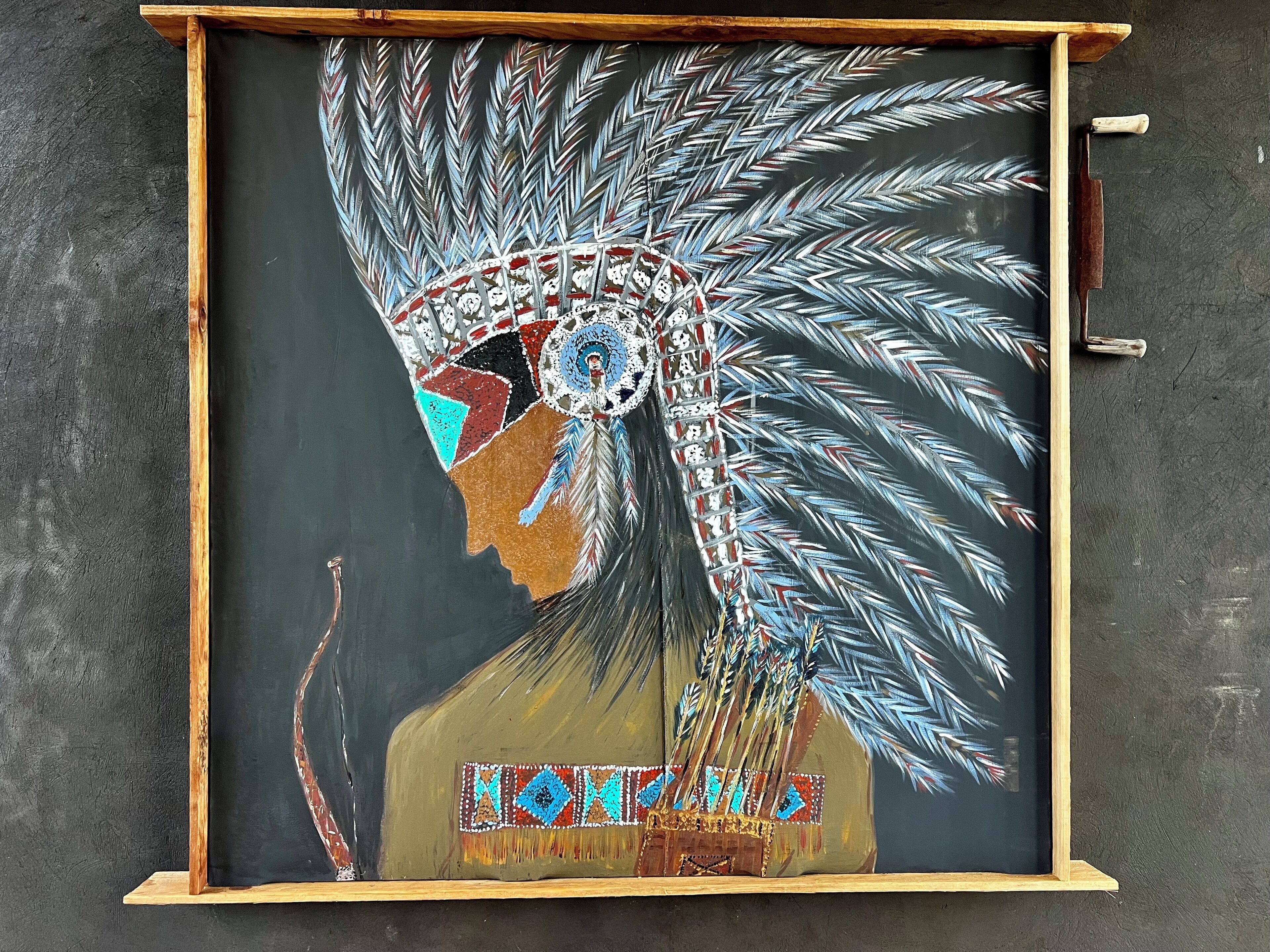 A framed artwork of a Native American headdress with feathers and beadwork.