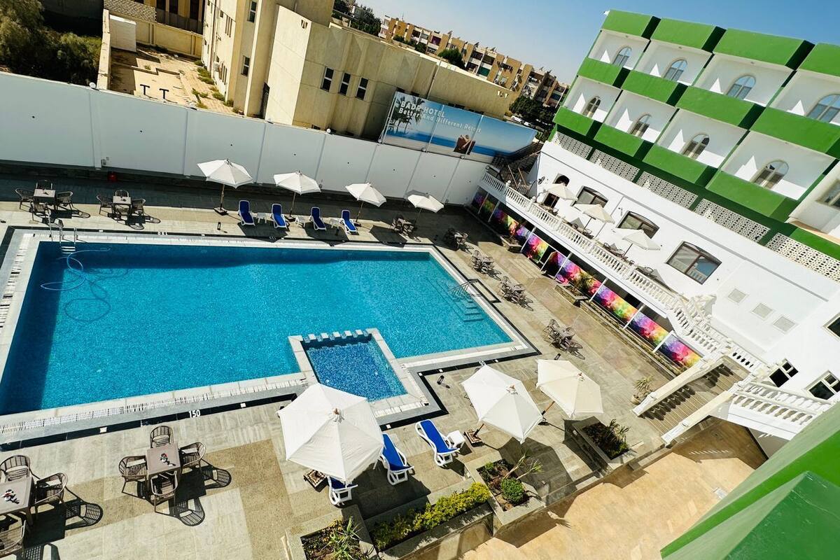 Ein Dachpool mit Liegestühlen und Sonnenschirmen, umgeben von Gebäuden.