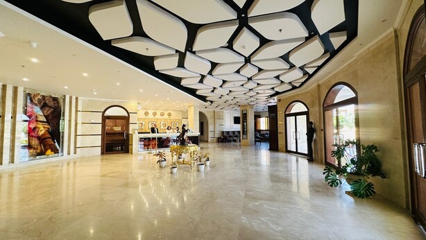 Eine großz ügige Lobby mit hoher Decke, einer Rezeption und einem großen Fenster.