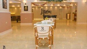 Eine Hotelhalle mit Kaffeebar, Sitzgelegenheiten und einer Rezeption.