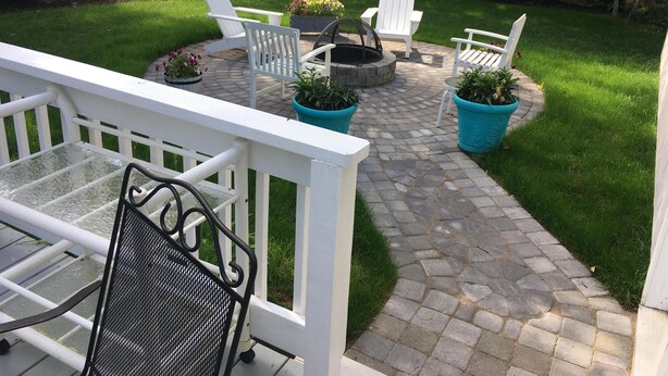 A patio with white Adirondack chairs, a fire pit, and potted plants. - Comfy Cape Home: Close to Mayflower Beach, golf course, and Downtown  (Dennis)