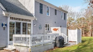 A two-story house with a covered patio, a grill, and a white fence. - Comfy Cape Home: Close to Mayflower Beach, golf course, and Downtown  (Dennis)