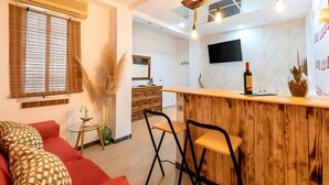 Un salon moderne avec un bar en bois, un canapé rouge et un téléviseur fixé au mur.