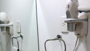 Une salle de bain équipée d’un lavabo, d’un miroir, d’un porte-serviettes, d’un sèche-cheveux et d’articles de toilette.