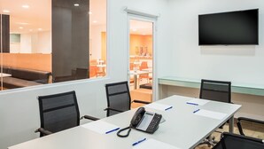 A conference room with a long table, chairs, a phone, and a TV on the wall. - One Irapuato (Irapuato)