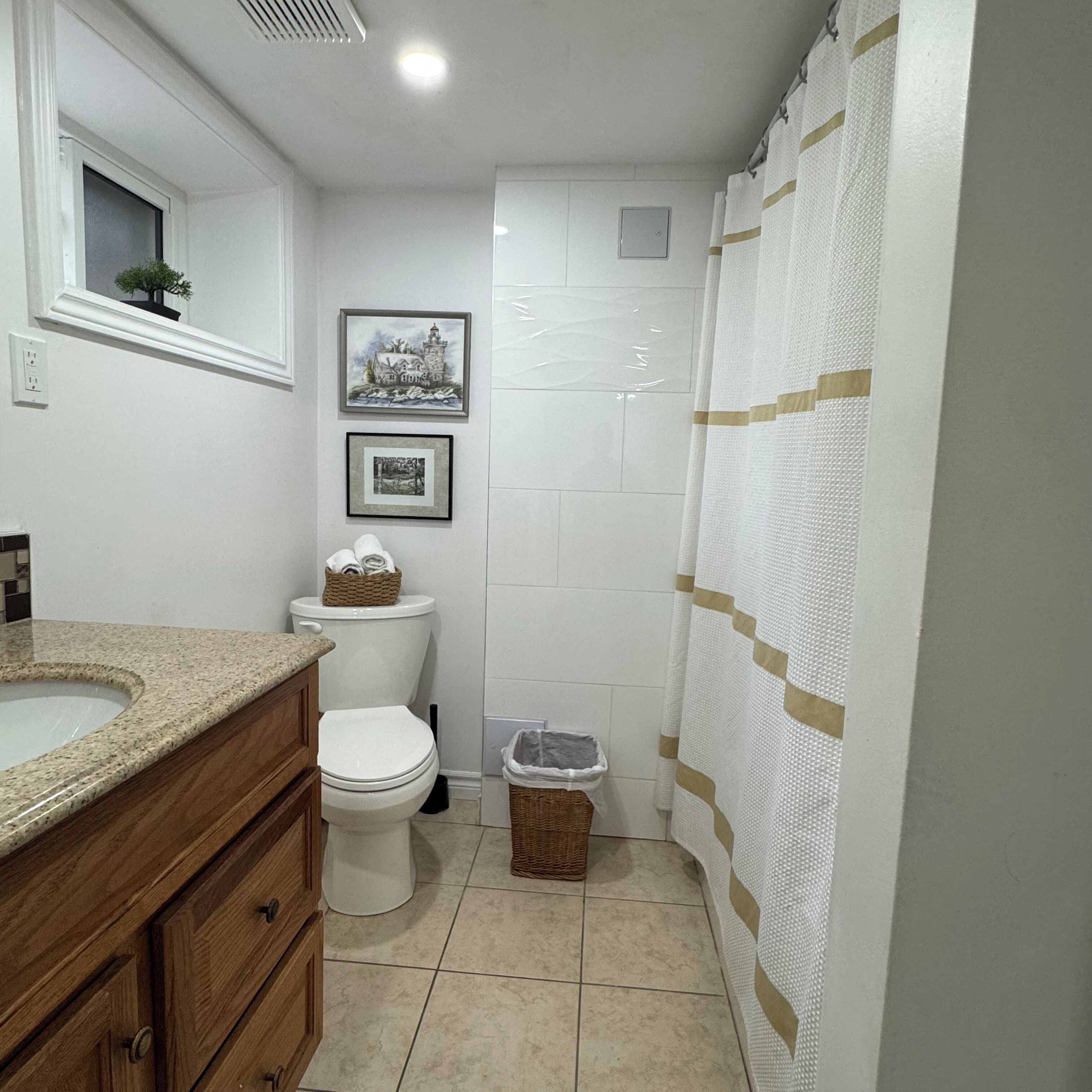 Une salle de bain équipée de toilettes, d’un lavabo, d’un miroir et d’un rideau de douche.