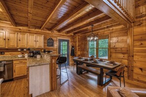 Ein Holzblockhaus-Innenraum mit Küche, Essbereich und einer Bar.