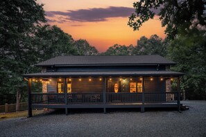 Ein zweistöckiges Holzhaus mit Veranda, umgeben von Bäumen.