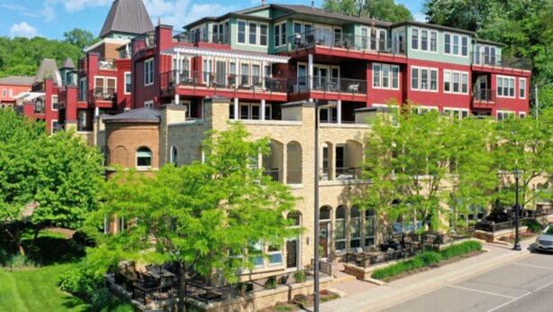 A multi-story building with a red and green facade, large windows, and a balcony.
