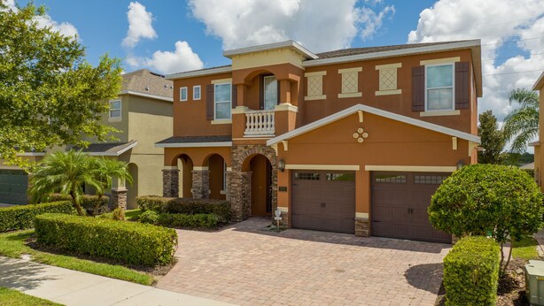 A two-story house with a brick driveway, a garage, and a small balcony. - Private Villa near Disney world (Kissimmee)