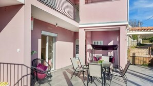 Un edificio a due piani con un balcone, un tavolo con sedie e una poltrona sospesa.