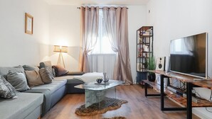 Un soggiorno con un divano, un tavolino, una televisione e una libreria.