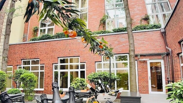 A courtyard with a metal bucket filled with bottles and ice, surrounded by wicker chairs and potted plants. - Lindner Hotel City Plaza Formerly Renaissance Cologne Hotel (Cologne)