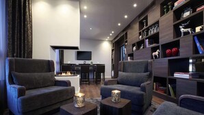 A modern living room with two grey sofas, a coffee table, and a bookshelf filled with decorative items. - Lindner Hotel City Plaza Formerly Renaissance Cologne Hotel (Cologne)