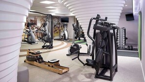 A modern gym with cardio machines, weightlifting equipment, and a mural on the wall. - Lindner Hotel City Plaza Formerly Renaissance Cologne Hotel (Cologne)