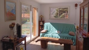 A living room with a green sofa, a wooden bench, a bookshelf, and a television on a stand.