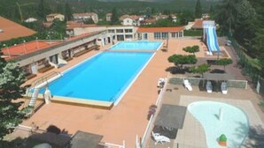 A resort with a large swimming pool, a water slide, and a view of the surrounding mountains.