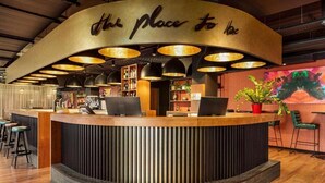 Een receptiebalie met een gebogen ontwerp, verlichting erboven en een bord met de tekst 'The Place to be'.