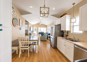 A spacious kitchen with a dining area, wooden flooring, and white cabinetry.