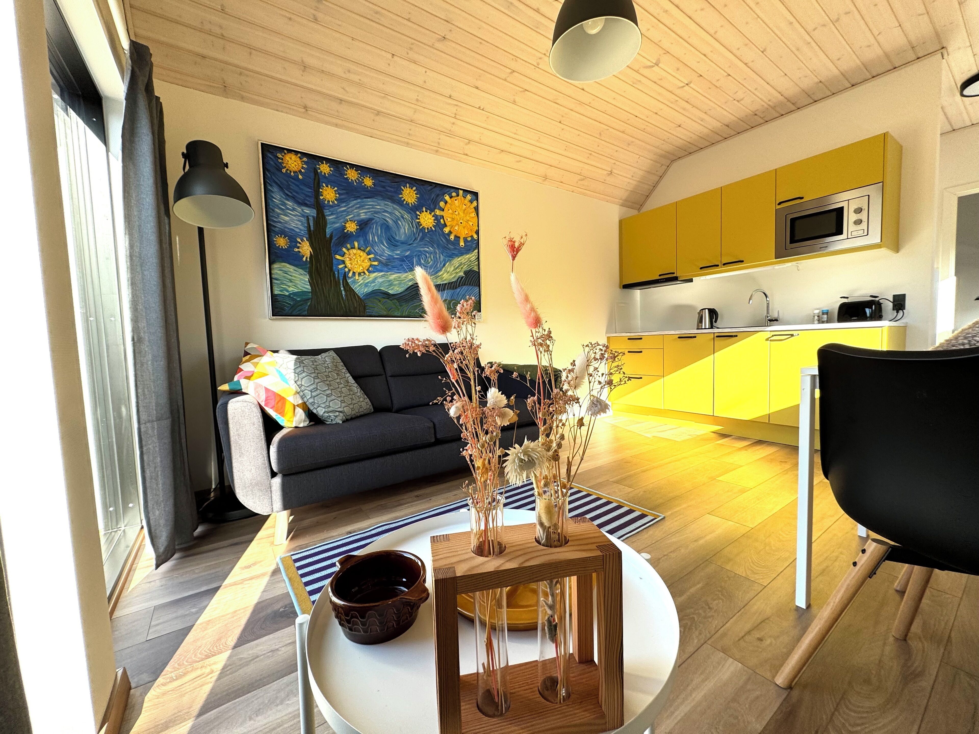 Una sala de estar moderna con un sofá, una mesa de centro con un jarrón y un cuadro en la pared.
