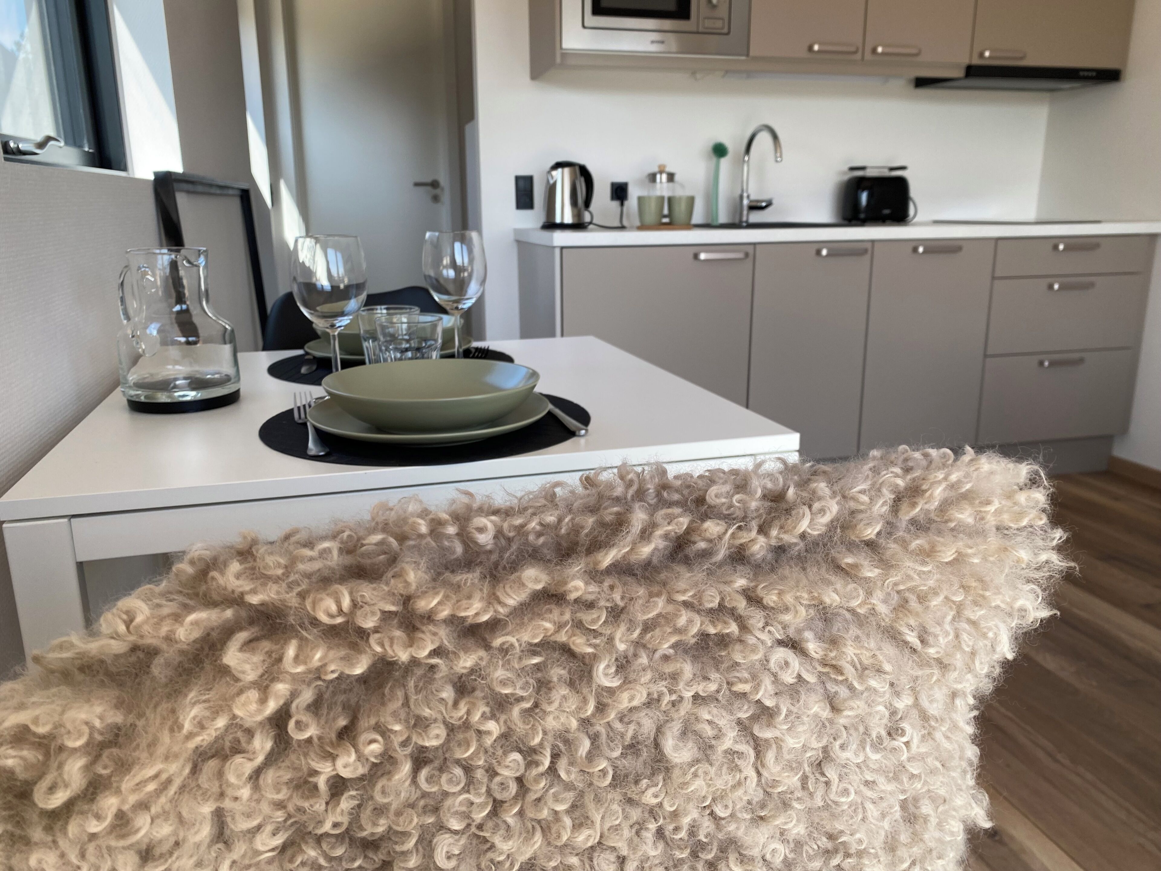 A modern kitchen with a dining table set for two, a microwave, and a sink.