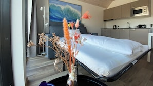 Una habitación de hotel con cama, escritorio, kitchenette y un amplio ventanal.