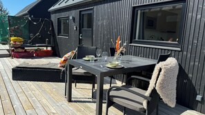 An outdoor dining area with a table set for two, surrounded by wicker chairs and a bench. - Esehytter Luxury Holiday Home near Beach (Norre Nebel)