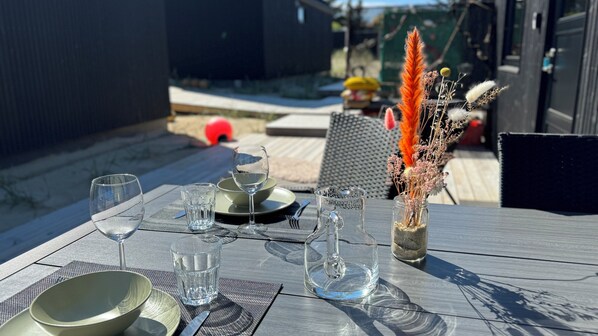 A table set for a meal with clear glassware, plates, and a decorative vase with dried plants. - Esehytter Luxury Holiday Home near Beach (Norre Nebel)