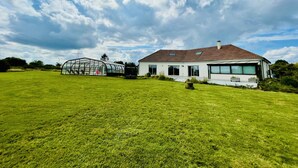 A modern house with a red-tiled roof, large windows, and a greenhouse structure. - Maison spacieuse avec piscine (Condé-sur-Risle)