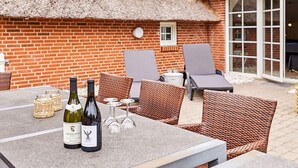 An outdoor seating area with wicker chairs and a table set with wine bottles and glasses. - Stunning home in Ulfborg with sauna (Ulfborg)