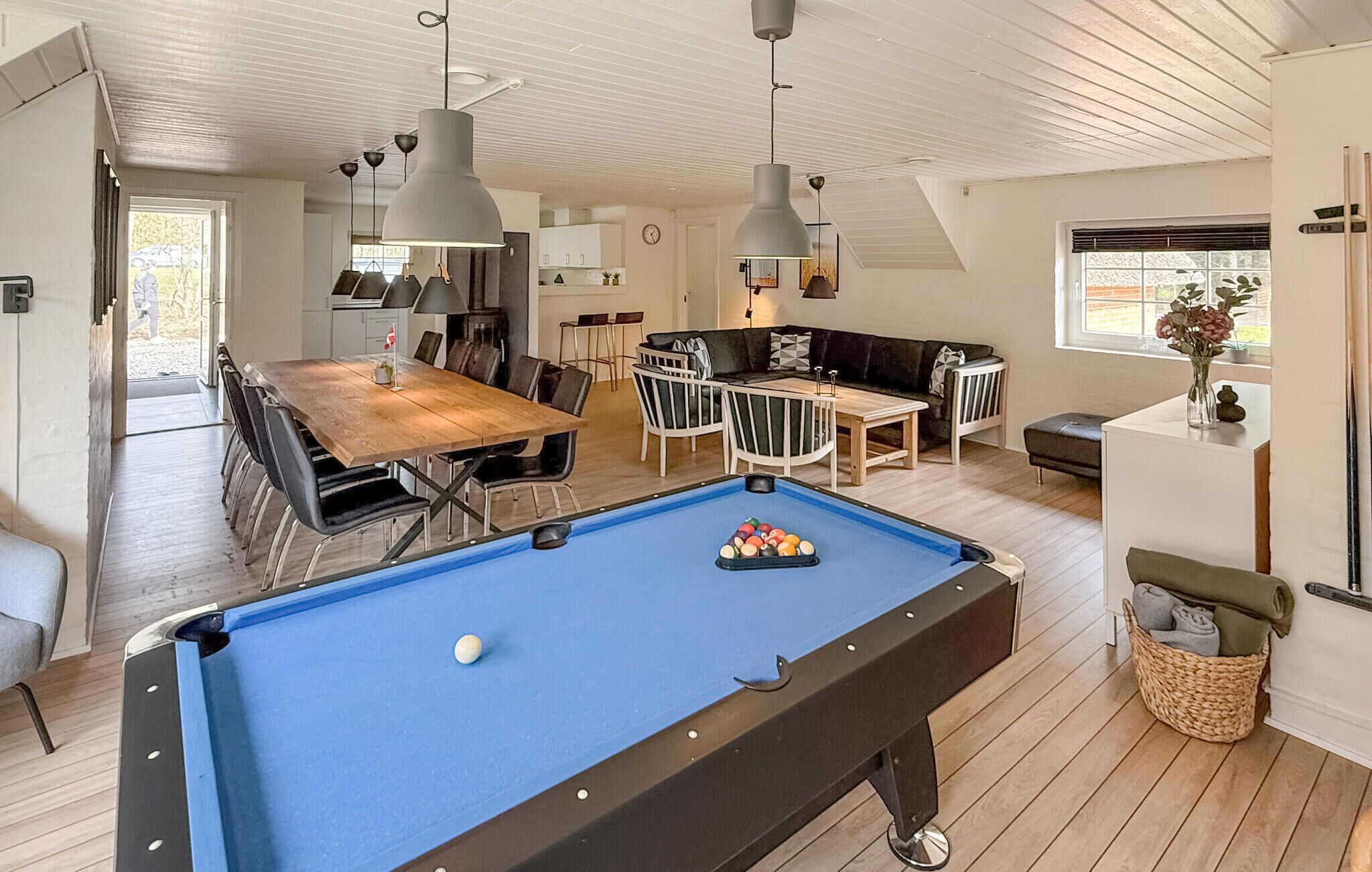 Une pièce spacieuse comprenant une table de billard, un coin repas et une cuisine.