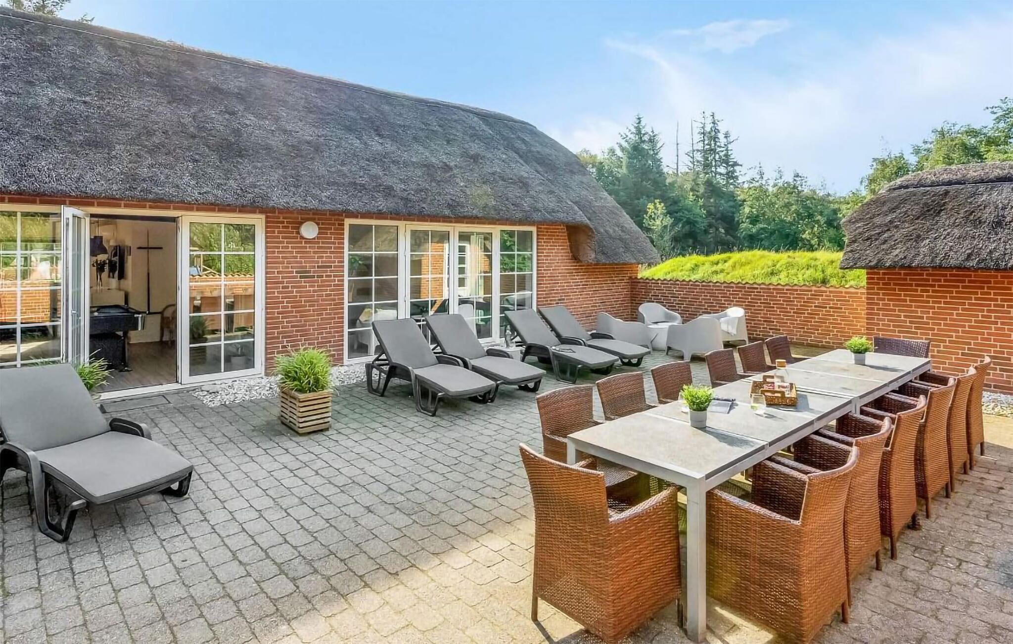Un espace patio avec un bâtiment à toit de chaume, des sièges extérieurs et une table de billard.