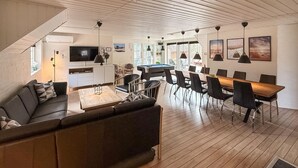 A modern living room with a sofa, coffee table, and dining area with chairs and a wooden table. - Stunning home in Ulfborg with sauna (Ulfborg)