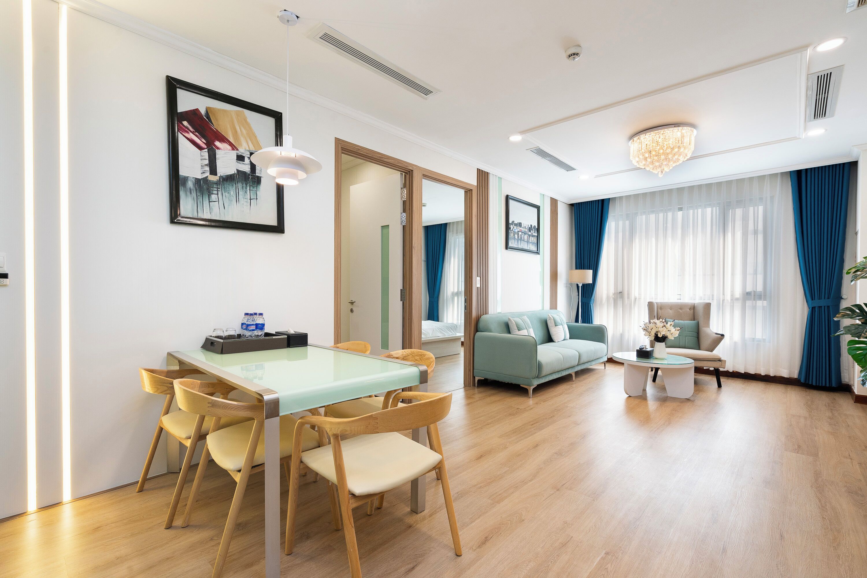 Een moderne woonkamer met een eethoek, houten vloeren en een kroonluchter.