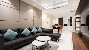 Ein modernes Wohnzimmer mit einem Ecksofa, zwei runden Beistelltischen und einem Essbereich mit Stühlen.