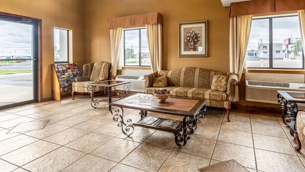 A spacious lobby with a high ceiling, a large window offering a view of the outside, a seating area with a sofa and chairs, and a coffee table with a bowl on it. - Rodeway Inn Santa Rosa, NM (Santa Rosa)